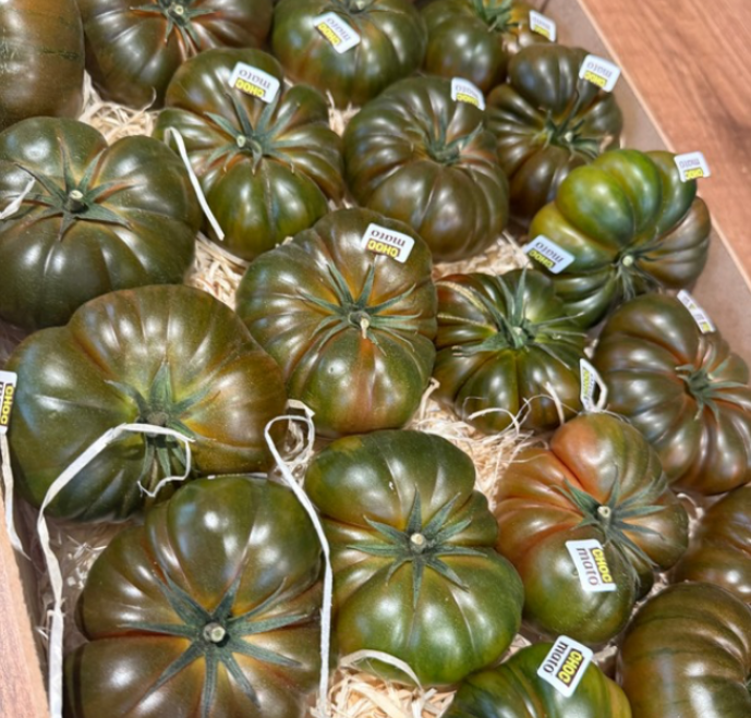 Tomates de temporada de la variedad 'Dono' en una caja, con etiquetas y decorados con paja.