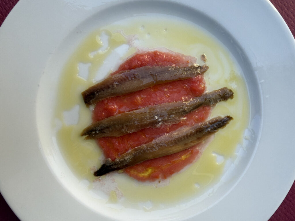 Plato de anchoas sobre tomate rallado con aceite de oliva en restaurante – Agencia Brilla.